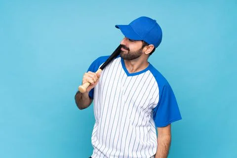 Young man playing baseball over isolated blue background laughing Stock Photos