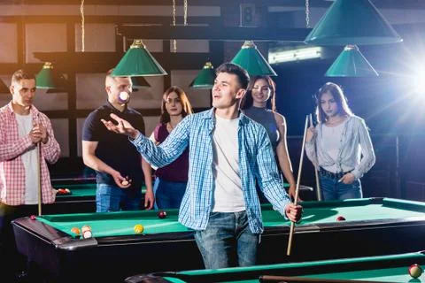 Young man playing in billiard. Posing near the table with a cue in his hands Stock Illustration