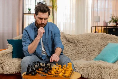 Young man playing chess alone making serious move deep thinking strategy Stock Photos