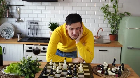 Young man playing chess on kitchen table. Male plays in logical board game with Stock Footage 150236181