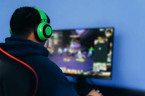 A young man playing a computer game on professional armchair against monitor in Foto stock