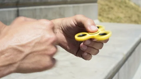 Young man playing with a fidget spinner Stock Footage 111275795
