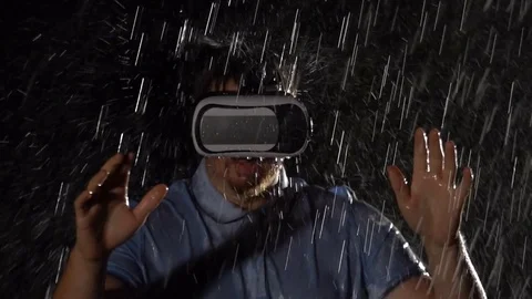 Young man playing game in virtual reality glasses in the rain. Technology concep Stock Footage 80250511