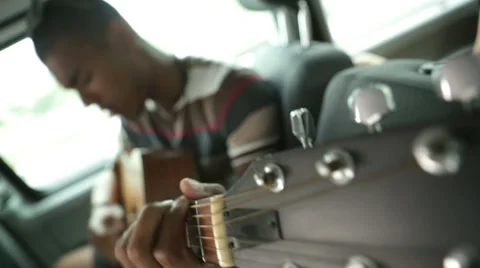 Young man is playing guitar during a travel in a moving van Stockbeeldmateriaal 64520094
