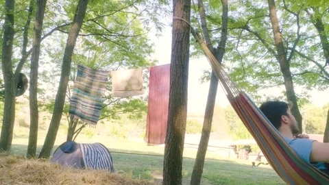 Young man playing guitar in the hammock Stock Footage 76903149