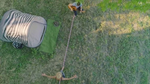 Young man playing guitar in the hammock. Young woman on the slackline Stock Footage 76916537