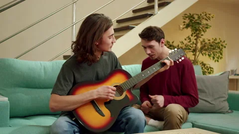 A young man is playing guitar for his friend and they both are singing Stock Footage 160171132