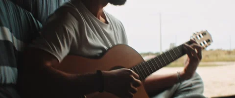 Young man playing the guitar sitting in the back of a van Stock Footage 203584205