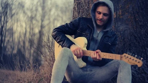 Young man playing guitar at sunset Видео 92387057