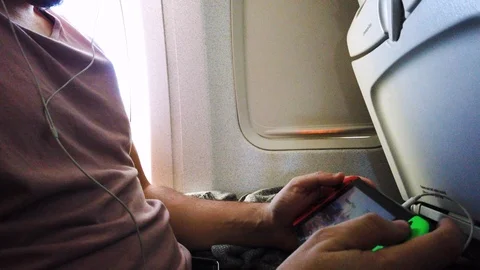 Young man playing handheld console on an airplane 4k Stock Footage 108552852
