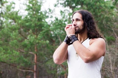 Young man playing the harmonica in a forest glade. Stock Photos