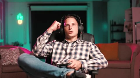 Young man playing online computer video game, colorful lighting Stock Footage 202877058