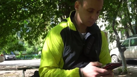 Young man playing the phone,in the background of green trees Stock Footage 75914649