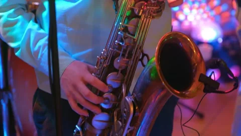 Young man playing saxophone in vibrant indoor club at nighttime Video stock 342128555