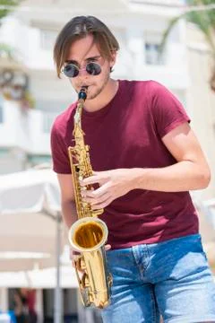 Young man playing a saxophone while looking at the camera. Music and lifestyl Stock Photos