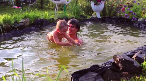 Young man playing with a small child in the pond Vidéo 64989698