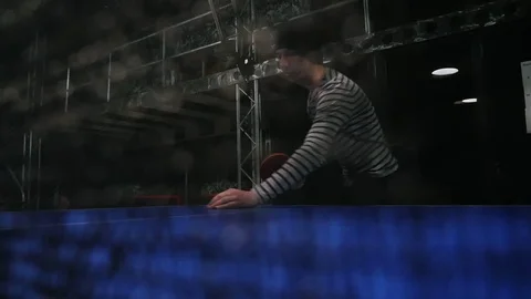 Young man playing table tennis in slow motion. Defocused black net on foreground 動画素材 103281685