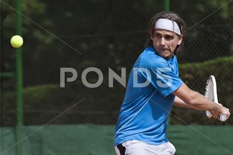 Young man, playing tennis on an outdoor court Stock Photos