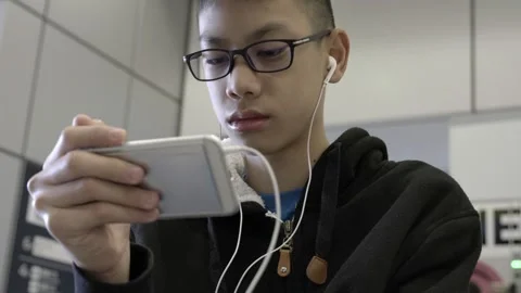 A young man is playing a video game on his phone while wearing headphones Video stock 314901326