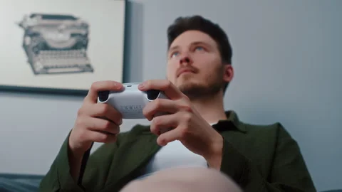 Young man playing video game with wireless controller at home Video stock 319442519