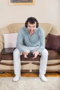 Young man playing video games with wireless Bluetooth joystick Stock Photos
