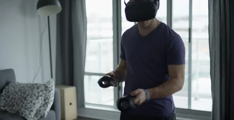 Young man playing VR in bright modern apartment Stock Footage 106848899