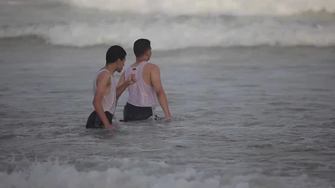 Young man playing with water and sand on the beach Stock Footage 148626224