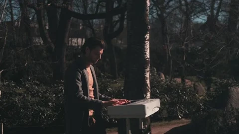 Young Man Playing White Digital Piano in Cinematic Forest Park Stock Footage 335102898