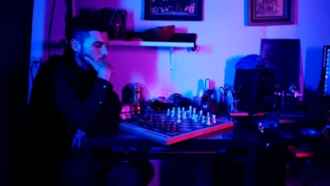 A young man plays chess with a blue background Vídeo Stock 139499812
