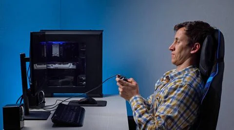Young man plays computer game using gamepad at table Stock Photos