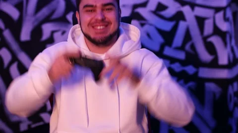 Young man plays on game console with gamepad sitting on chair Stock Footage 204029158