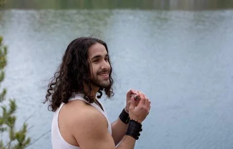Young Man plays the harmonica alone outdoor near the lake Foto stock