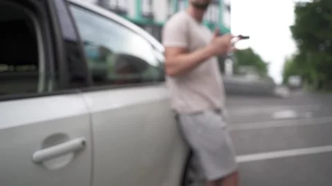 A young man plays with keys while leaning on a car. Stock Footage 279971422