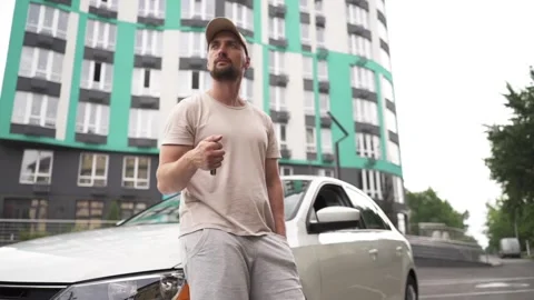 A young man plays with keys while leaning on a car. Stock Footage 279971471