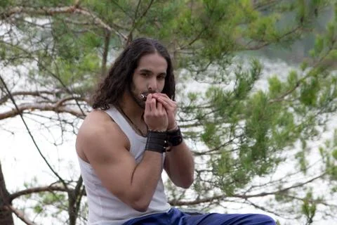 Young man plays a lip harmonica in nature. Foto stock