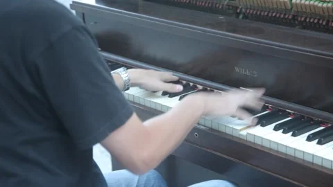 Young man plays an open upright piano on a street Stock Footage 341032996