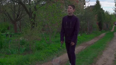 A young man plays with a racket and a shuttlecock in badminton. Slow-mo Stock Footage 75921207