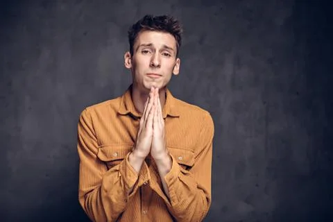 Young man with please gesture on dark background Stock Photos