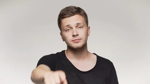 Young man pointing finger at camera. Isolated gray background Stock Footage 110788106