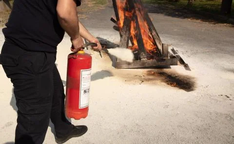 Young man pointing a powder type fire extinguisher forwards Stock Photos