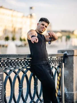 Young man pointing at viewer, standing by urban bridge railing in a city Stock Photos
