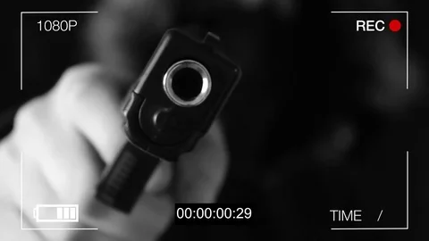 The young man points the gun at the hidden camera,black background Stockbeeldmateriaal 73715434