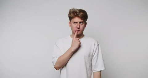 Young man pondering with curious expression in a minimal studio setting, ca.. Stock Footage 313273678