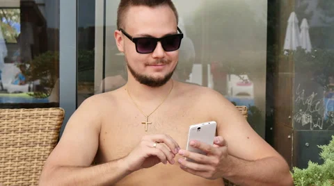 A young man by the pool talking on the phone Stock Footage 53343348