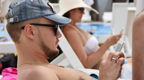 A young man by the pool talking on the phone Stock Footage 53771489