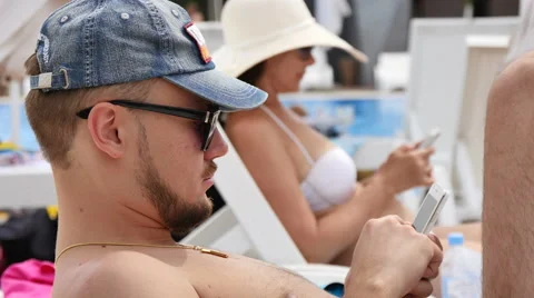 A young man by the pool talking on the phone Stock Footage 53771559