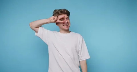 Young man poses in front of blue wall showing different facial expressions .. Stock-Footage 331990888