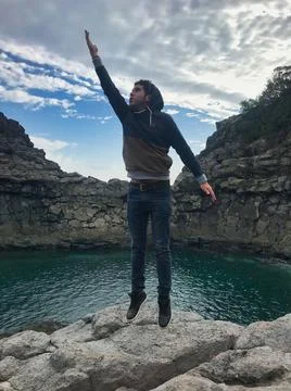 Young man posing and jumping on the sea side Stock Photos