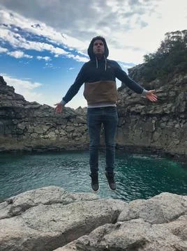 Young man posing and jumping on the sea side Stock Photos