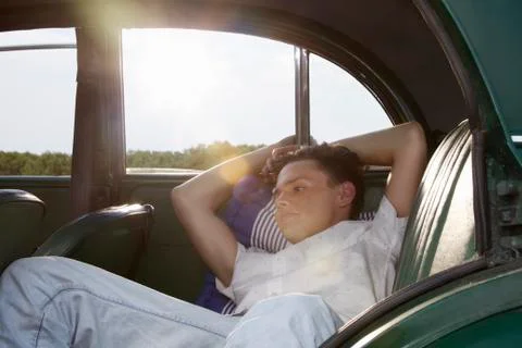 Young man posing in back seat of vintage morris minor Stock Photos